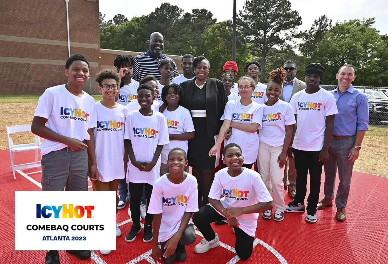Shaquille O'Neal and a group of individuals posing for a photo on a basketball court at the 2023 Icy Hot Comebaq Courts event in Atlanta. The photo features the basketball legend and other participants in a joyful pose. A label on the lower-left corner of the image displays the Icy Hot Comebaq Courts logo, along with the event's year (2023) and location (Atlanta).
