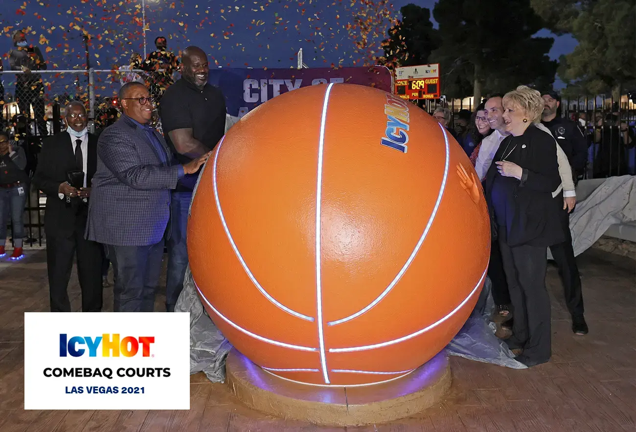 Shaquille O'Neal at the event on the newly renovated basketball court in Las Vegas, surrounded by several people, all gathered around a striking giant basketball figure adorned with the iconic Icy Hot logo on top.  The lower-left corner of the image features a label displaying the Icy Hot Comebaq Courts logo, along with the event's year (2021) and location (Las Vegas).