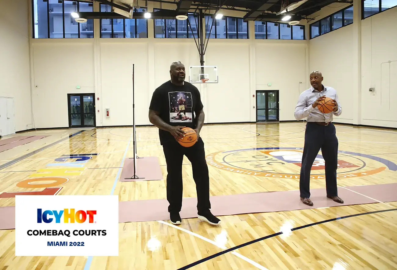 Shaquille O'Neal and Alonzo Mourning standing side by side, each holding a basketball ball, on the newly renovated basketball court at Overtown Youth Center (OYC) in Miami, Florida. In the lower-left corner of the image, a label displays the Icy Hot Comebaq Courts logo, along with the event's year (2022) and location (Miami).