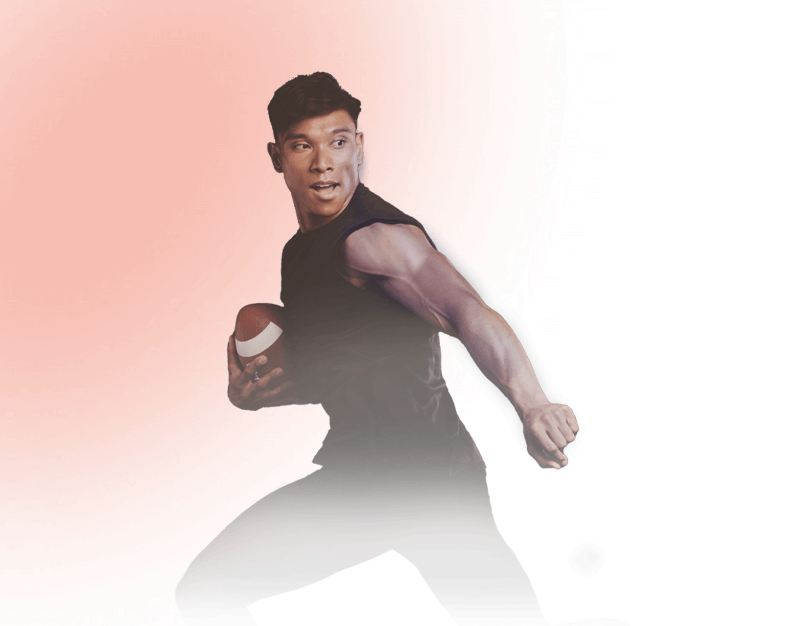 A man holds a football, and looks over his shoulder.