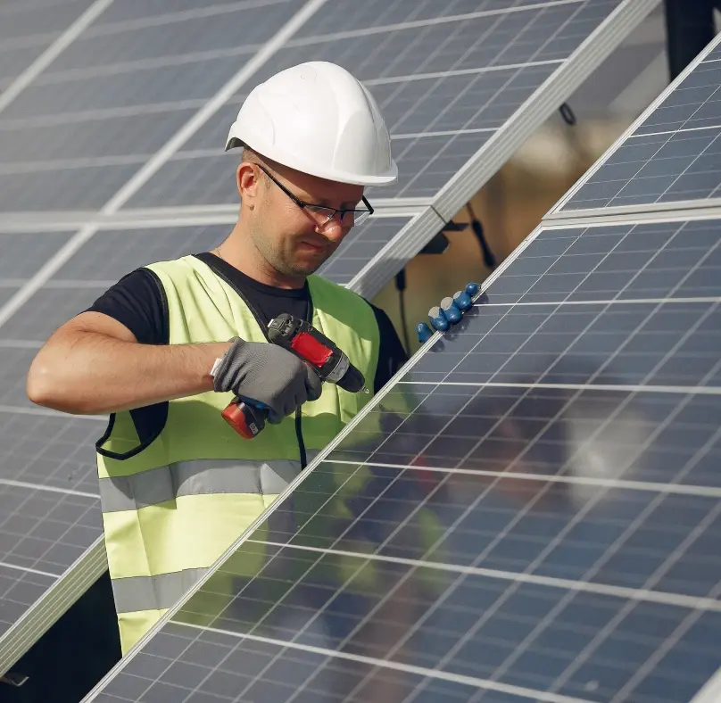 Un homme portant un casque de sécurité et un gilet de sécurité travaillant avec diligence sur des panneaux solaires.